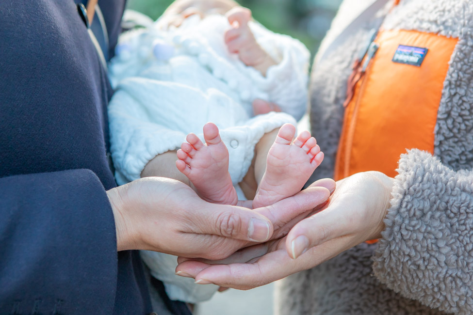 お宮参りの時に撮った赤ちゃんの足を父と母の手で包み込む写真
